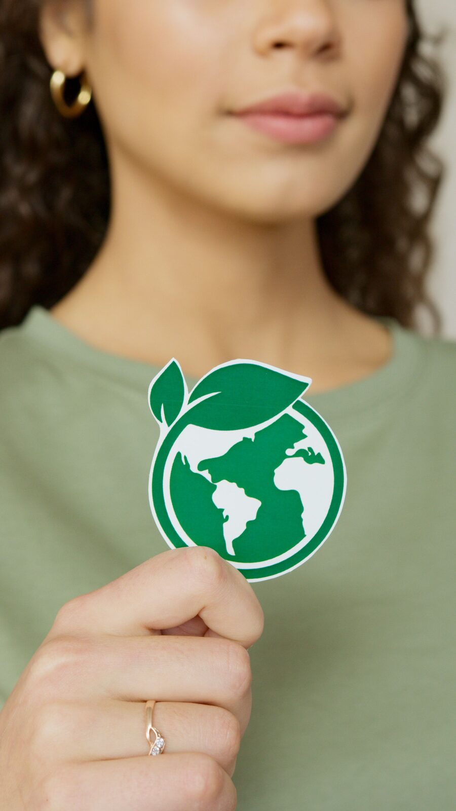 A hand holding a green recycling-earth sticker