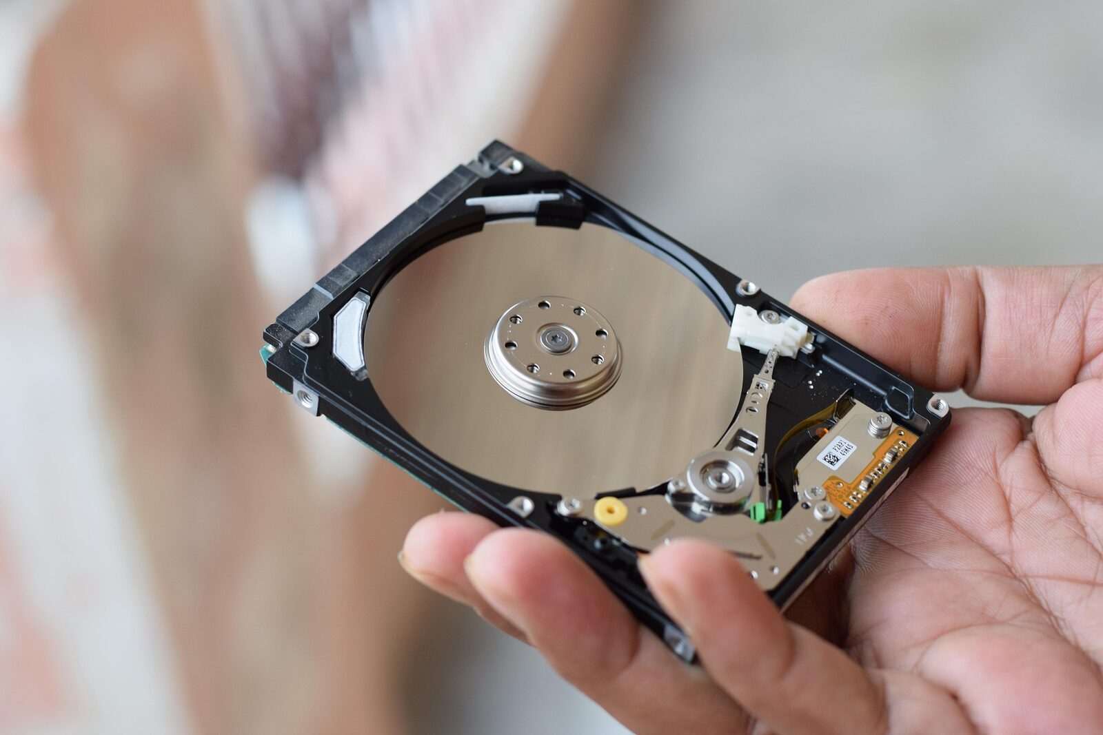 A hand holding an opened hard-disk drive